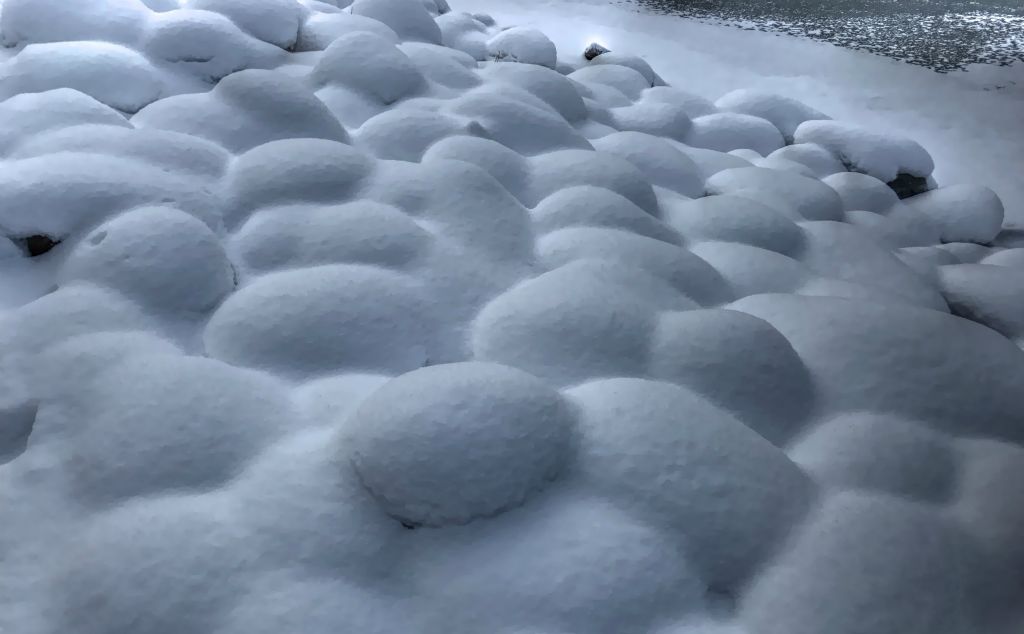 Some snow covered stones by the lake.