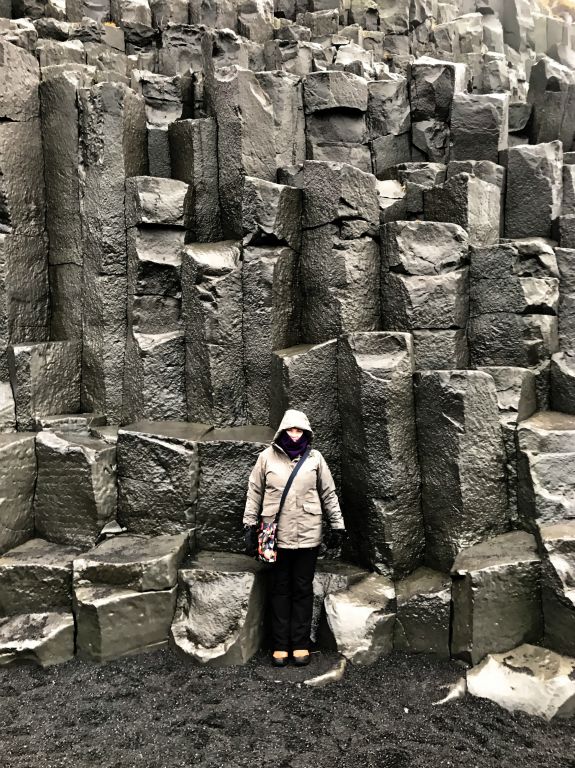 A period of time later we made it to Reynisfjara Beach, where the weather was proper awful. It was raining, freezing cold and blowing a gale. But despite all of this it was also very scenic so we went for a look.Here's Judith by the basalt columns  on the beach.