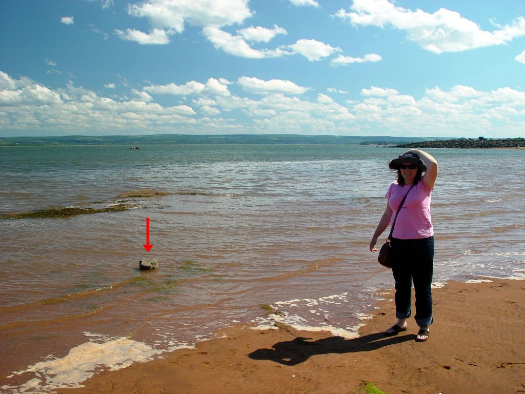 Scots Bay, about 20 miles north of Wolfville, is on the Bay of Fundy, which is famous for having the highest tides in the world. The water level changes by over 40 feet with every tide. To give you an idea how quickly the tide comes in, here's a picture of Judith standing by the water. Notice the rock poking out of the water (under the big red arrow that I have added for your convenience).