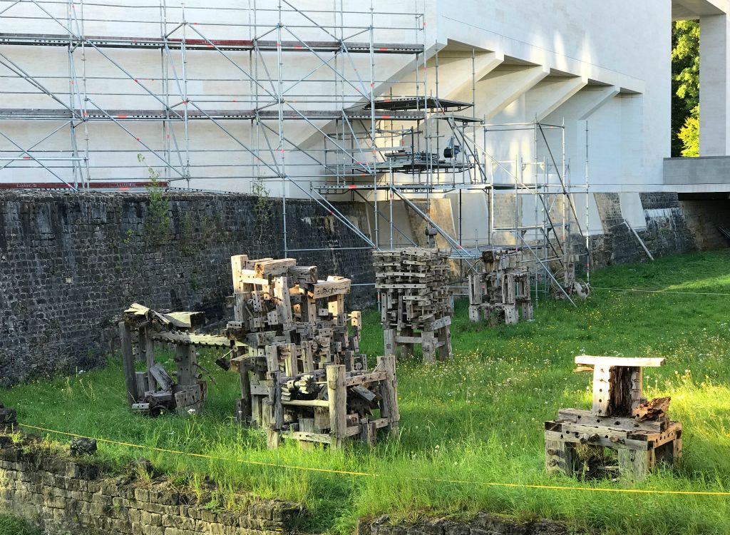 Presumably the wooden crap on the lawn in some sort of exhibit. However, being the Museum of Modern Art it is unclear as to whether the scaffolding is there for maintenance purposes or is also an exhibit itself. Or maybe it's both?I hate modern "art".