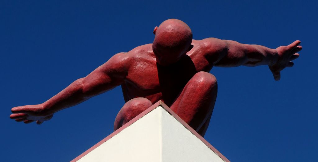 A red man on top of a tall plinth.